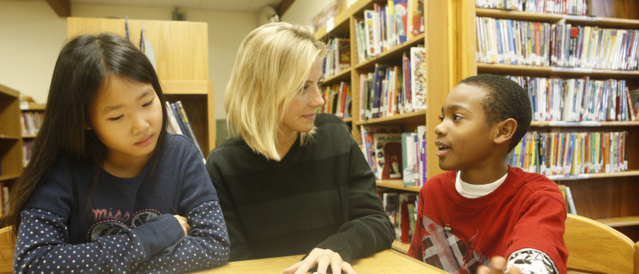 Woman at a table teaching two toddlers