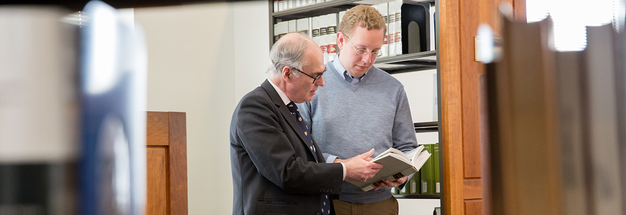Two faculty members reading together in the library