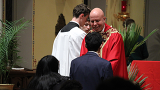 Fr. Colin receiving the gifts from students during Palm Sunday Mass