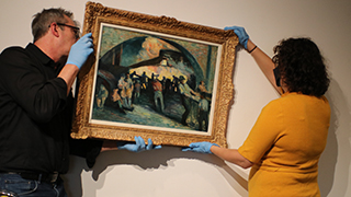 John Walako and Laura Hapke hang a painting.