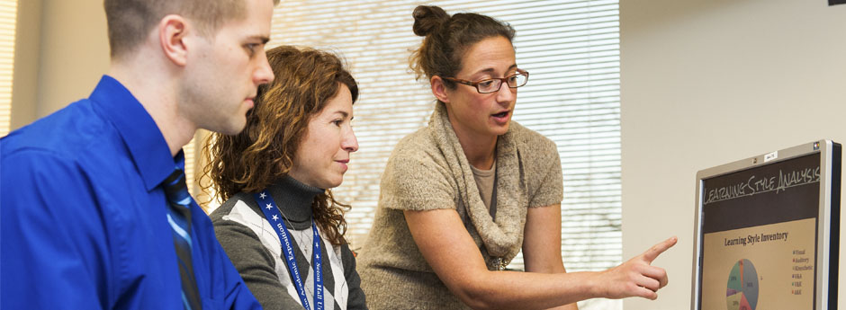 Three people looking at a computer.