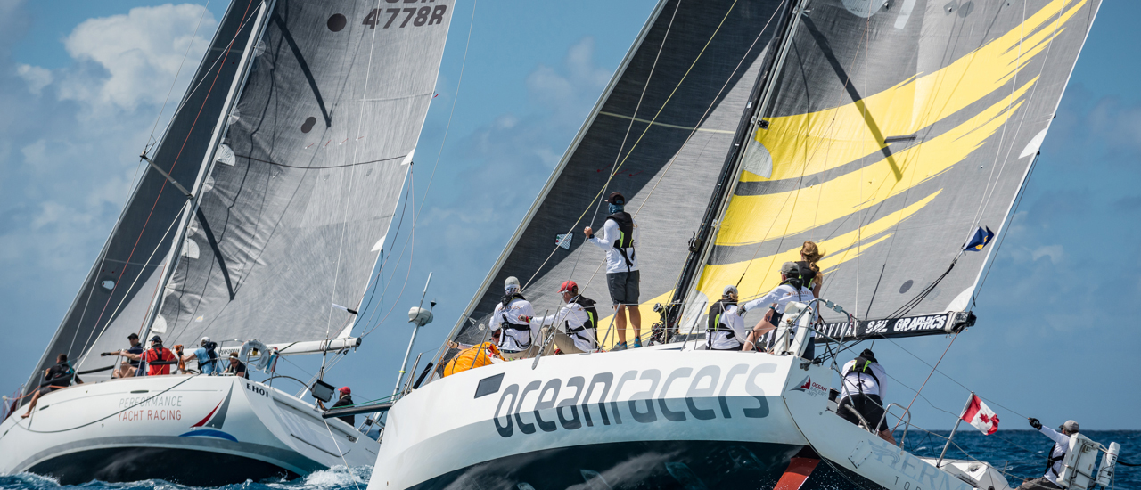 Two sailboats with their crews out on the ocean.