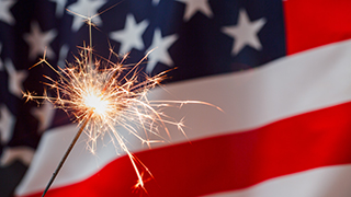 A sparkler in front of the American flag.