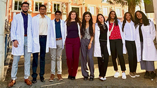 Students wearing their white coats posing for a group photo during a study abroad trip.