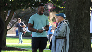 father talking to student on the green