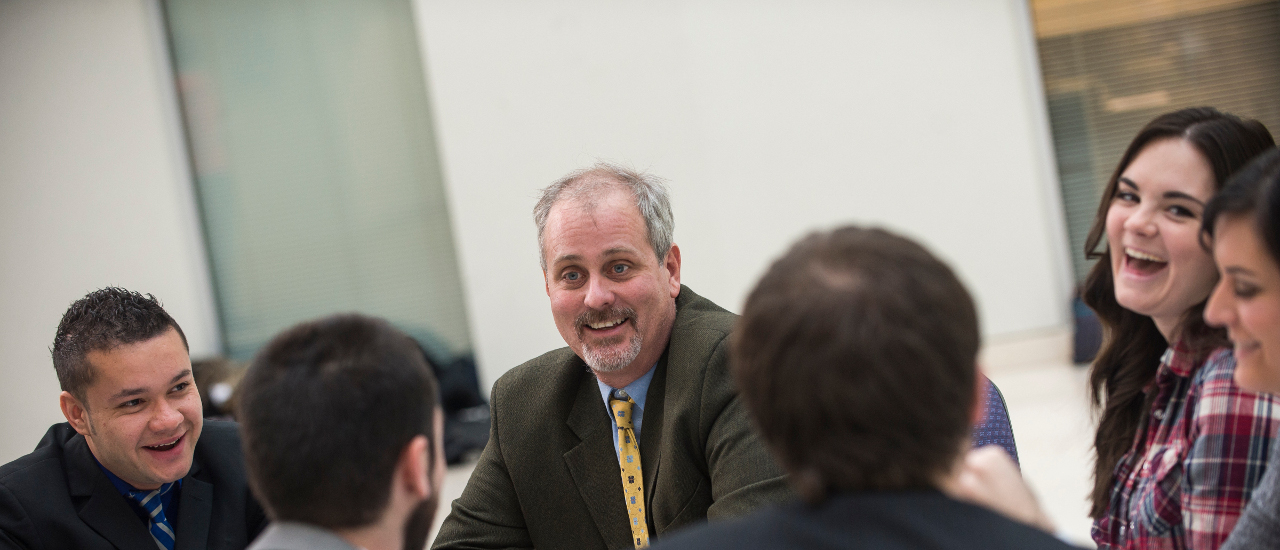 Group of students talking with a professor.