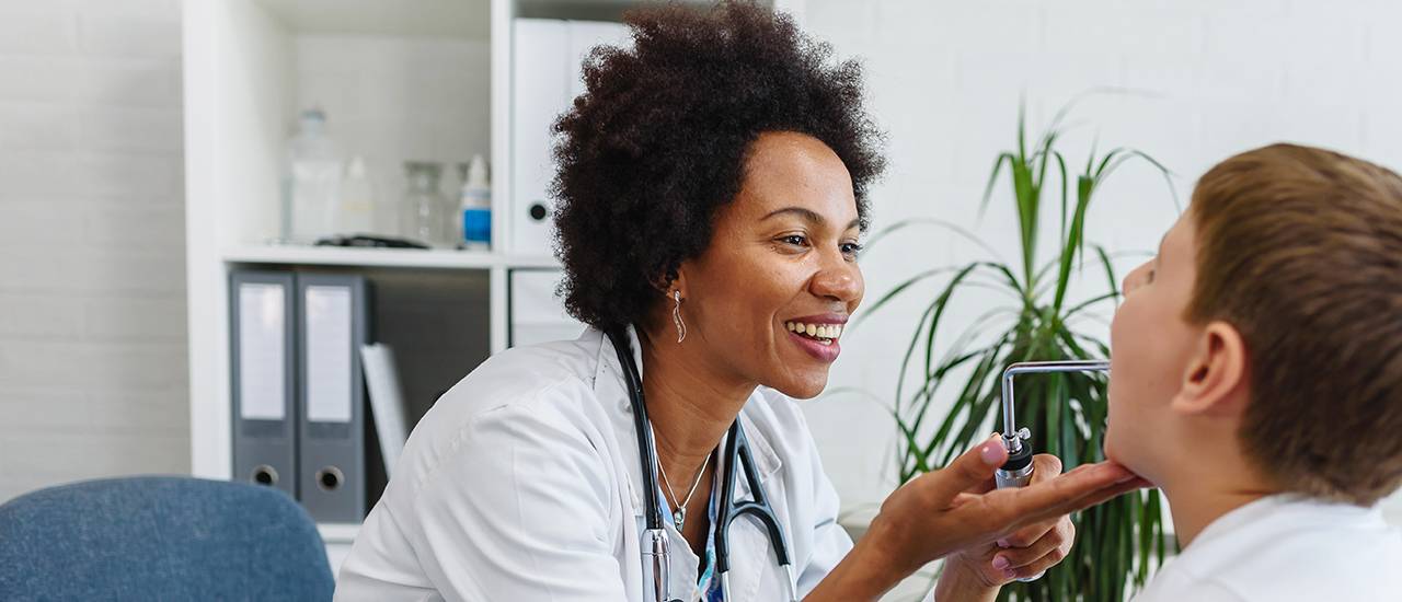 A Family Nurse Practitioner looking at the throat of a patient.