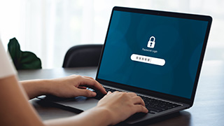 Person typing on a laptop with a password login screen displayed.