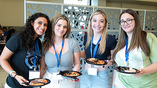 Students eating lunch Image of four students each holding a plate in the University Center.