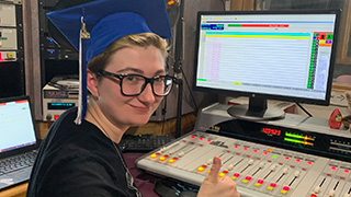 Rachel Haggerty in WSOU booth with graduation cap 