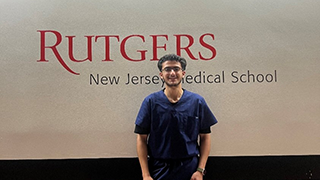 student posing with rutgers school sign in the background 