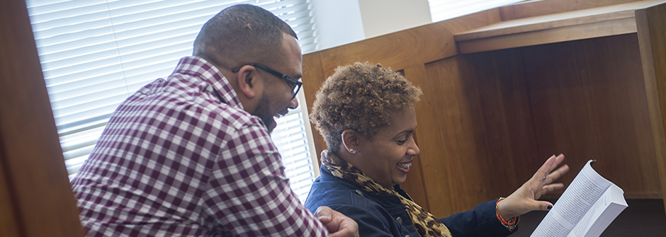 Social Work professor speaking to student at a desk in the Library.