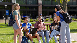 Students laughing on bench on campus